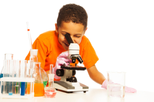 serious-8-years-old-black-boy-with-short-hair-in-chemistry-lab-class-with-microscope-and-test-tubes-on-the-table